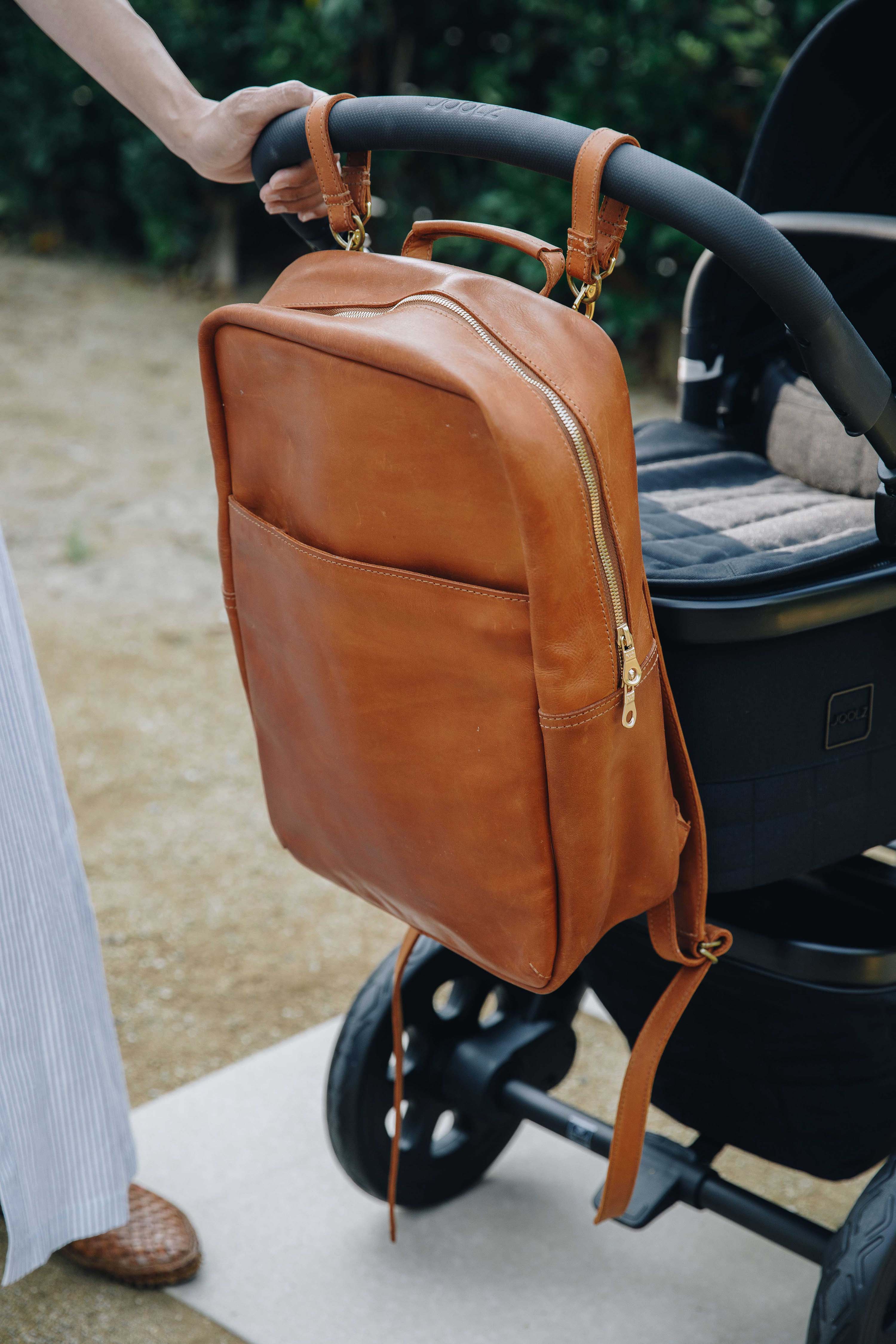 brown leather diaper bag packpack hanging on stroller